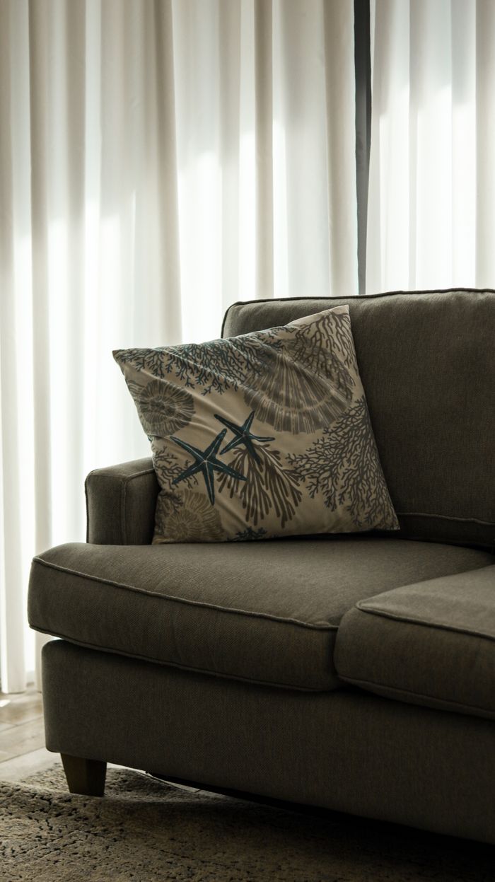 Elegant couch with starfish-themed pillow in sunlit living room.